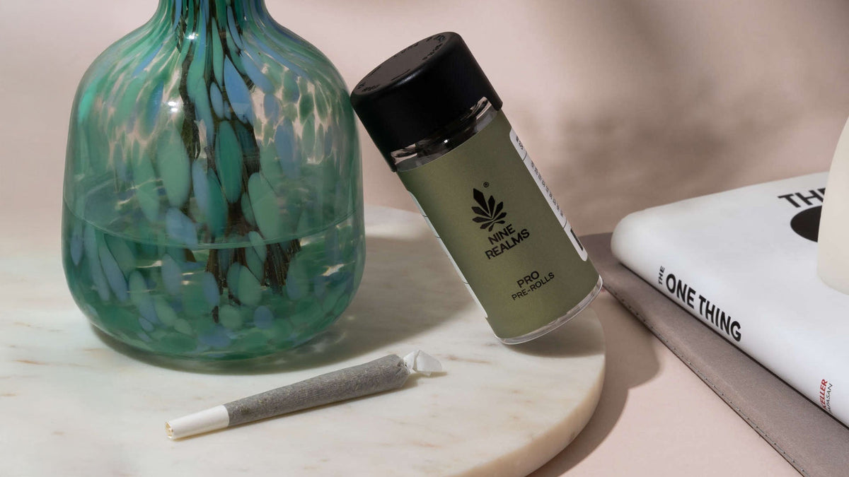 Nine Realms AK-47 strain pre-rolls next to a book and a vase