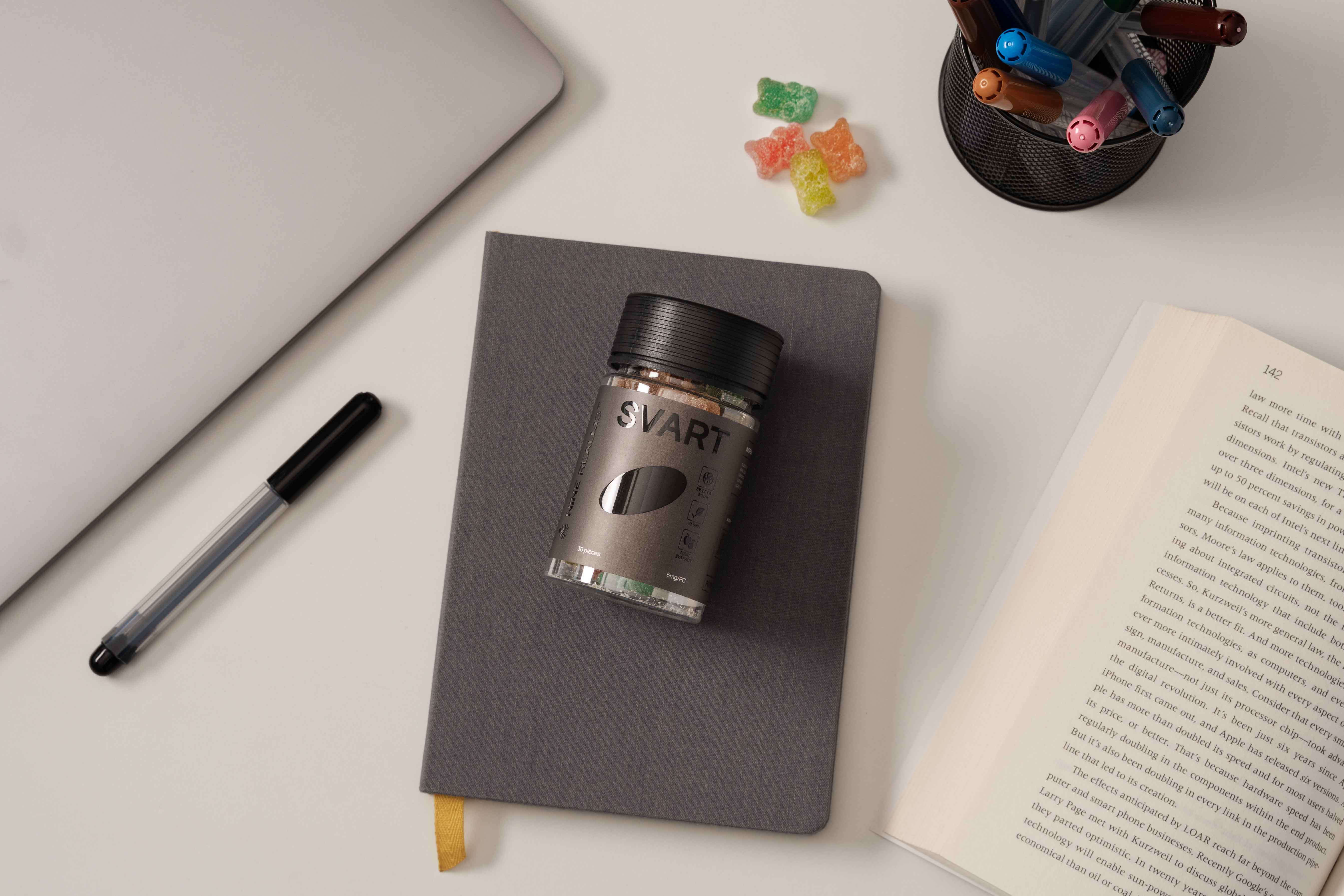 Nine Realms SVART THC Gummies on a grey journal and a macbook nearby