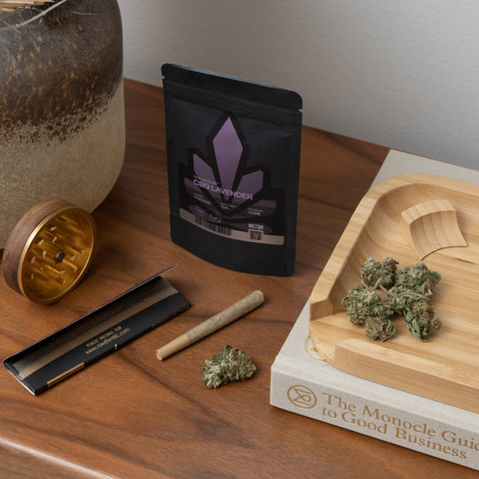 Cannabis flower buds in the rolling tray with rolling papers and pre-rolled joint