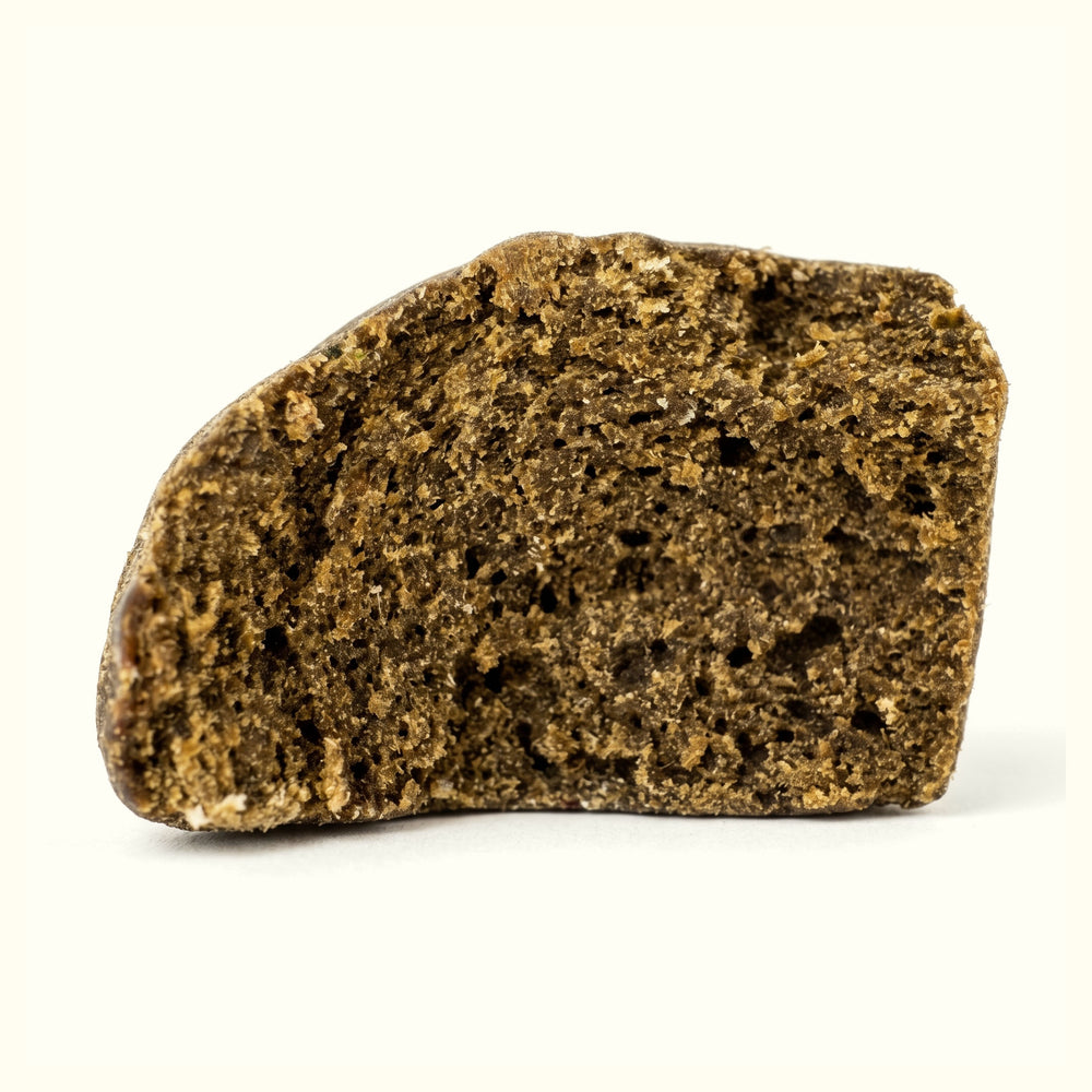 Nine Realms LIGHT Static Sift Hash close-up: porous, golden-brown hash chunk on a cream background