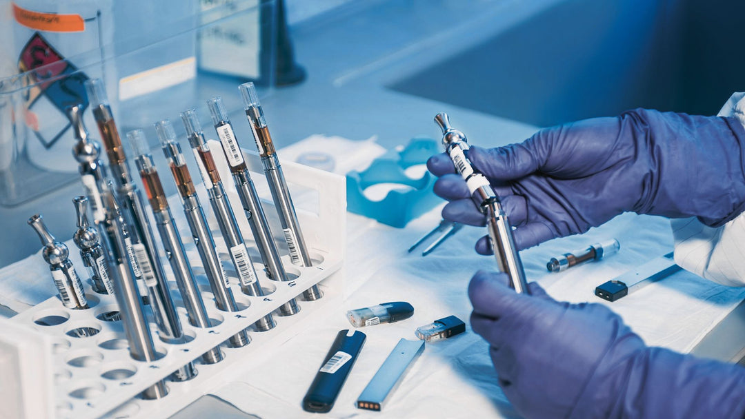 Behandschuhte Hände beim Umgang mit Vape-Kartuschen in einer Laborumgebung