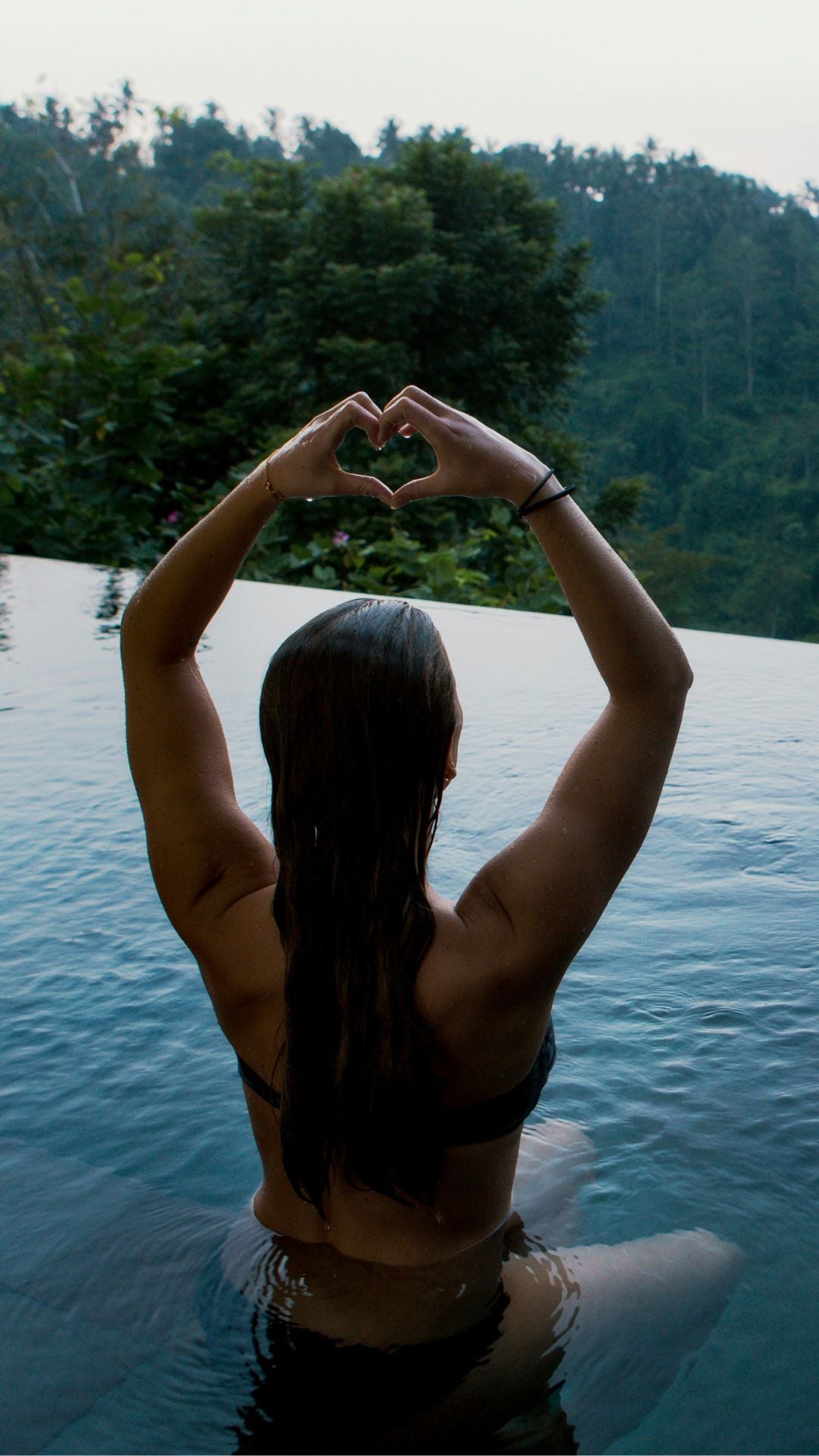 Woman sitting in a pool, showing heart emoji because she loves nine Realms CBD products